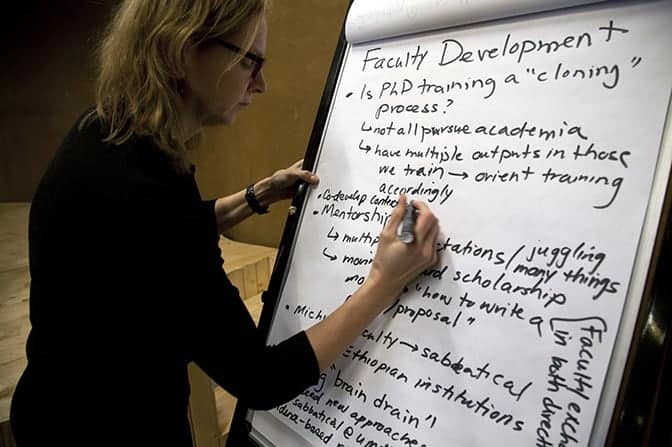 A professor writes on a whiteboard.