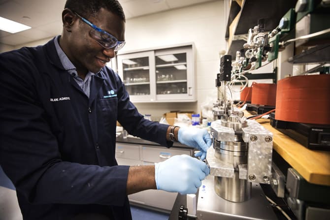 A student wears safety goggles and performs a laboratory test with some machinery