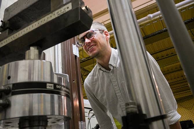 A person wears safety goggles and examines machinery