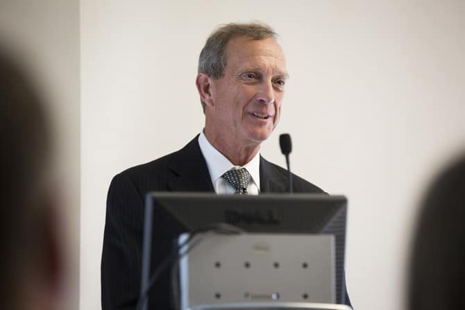 Joseph Malloure stands before a podium, delivering a speech