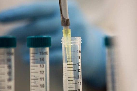 Close-up of a researcher inserting a syringe into a vial