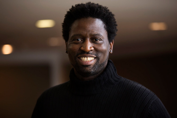 A Black man, Herek Clack, smiling at the camera. He's wearing a black turtleneck