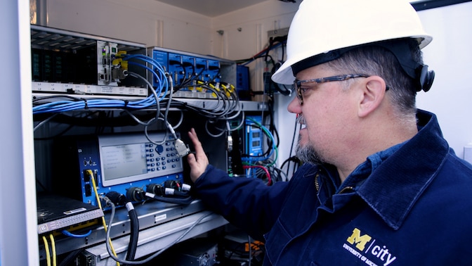 Mcity Test Facilities Manager, Jim Lollar, looks inside a traffic signal cabinet at Mcity on Thursday, November 30, 2023.